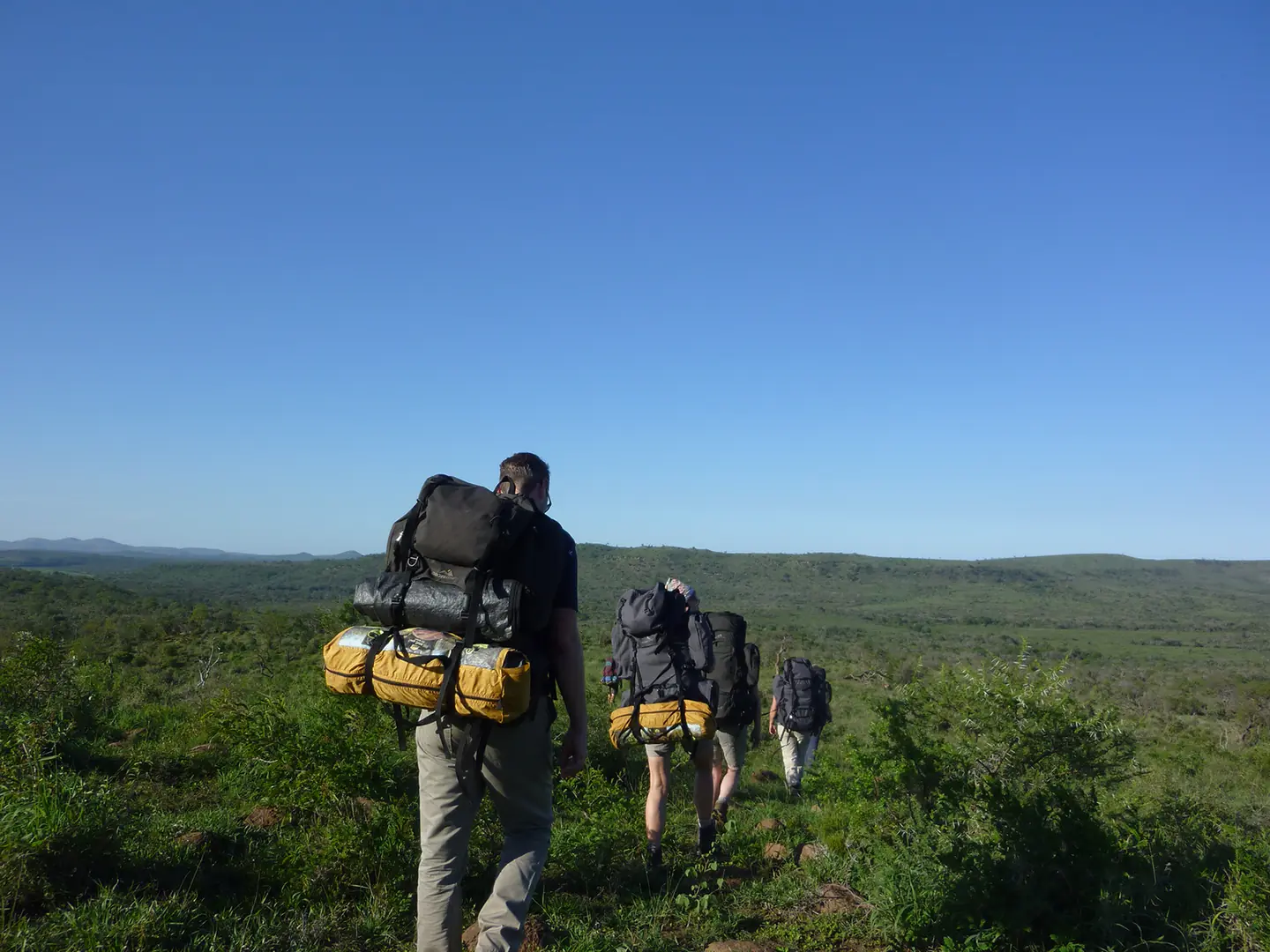 Mensen lopen met rugzakken in het Zuid-Afrikaanse wild tijdens een van de natuurpaden van de Kenchaan Foundation.