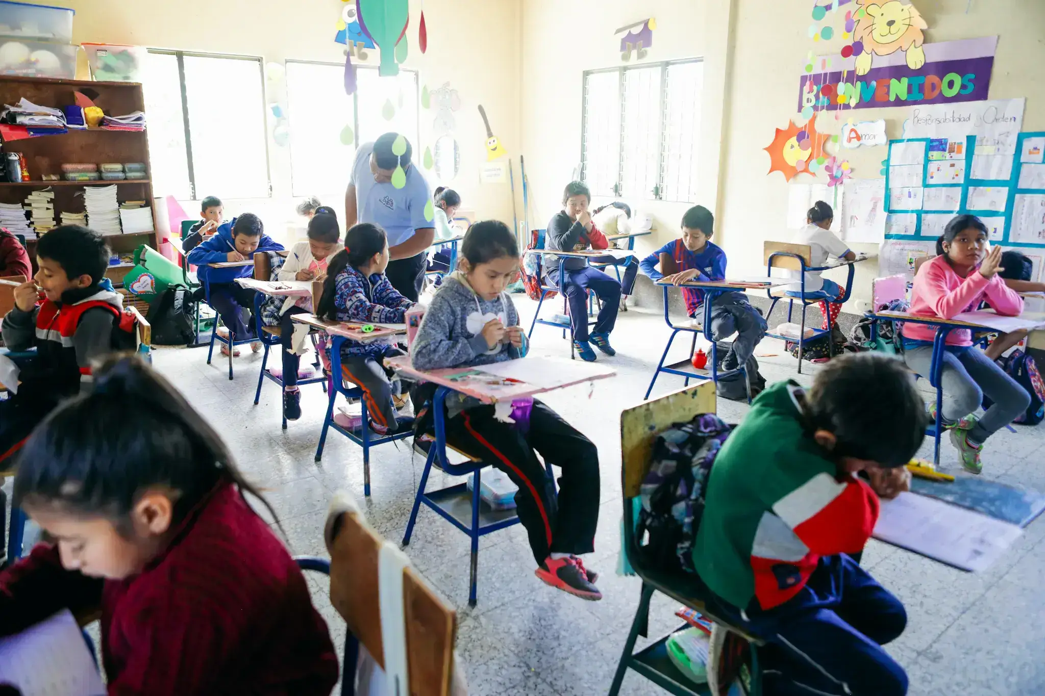 Een klaslokaal van één van de scholen van Niños de Guatemala waarin de kinderen druk aan het leren zijn. 
