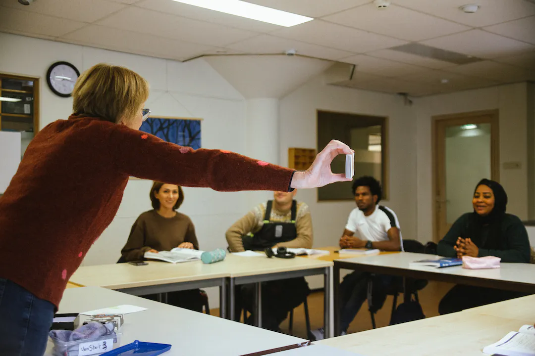 Volunteer teaches Dutch language to a group of newcomers at BOOST Amsterdam